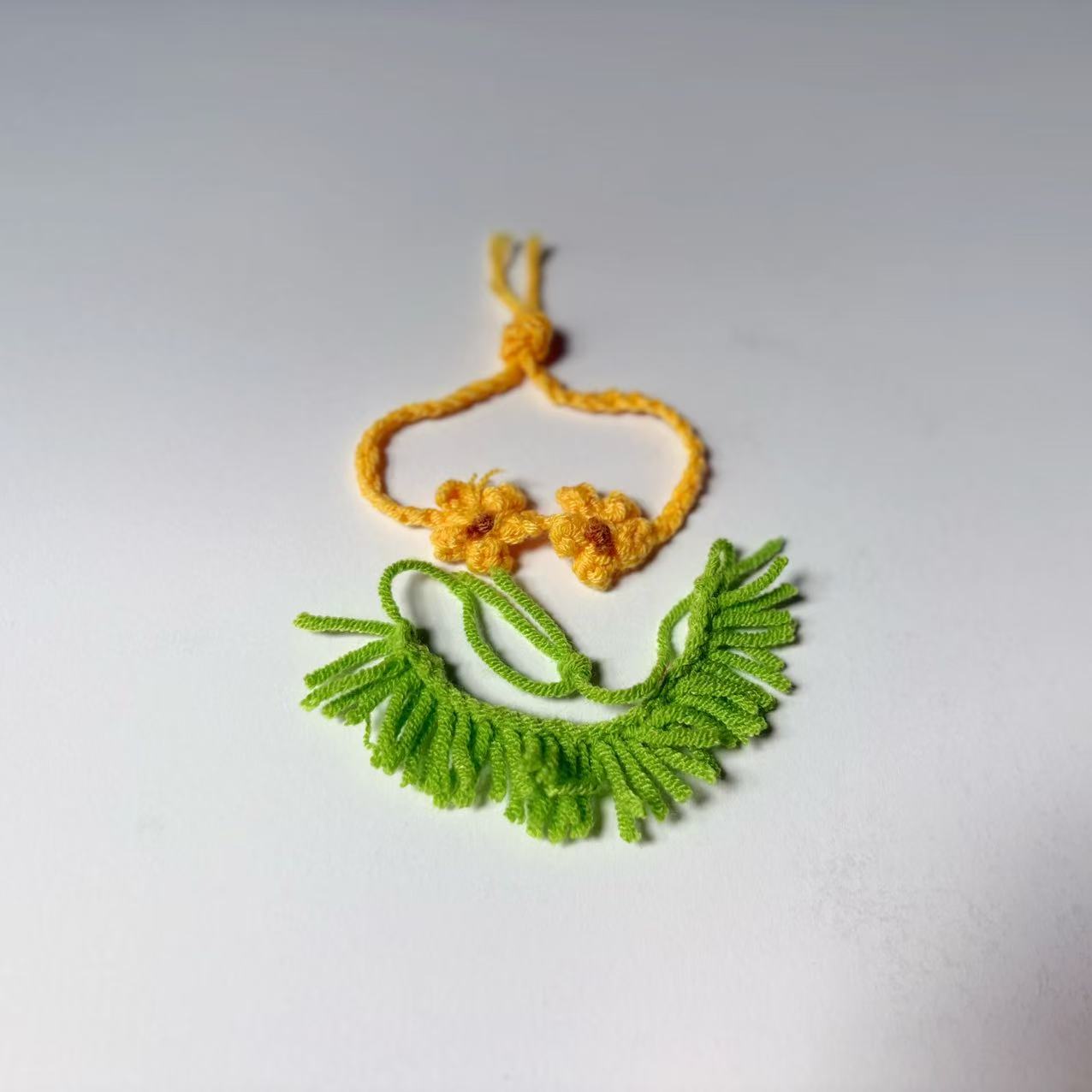 Green and yellow crocheted necklace on a white background