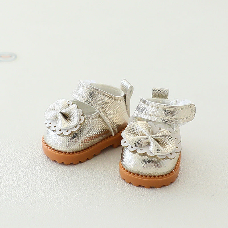Pair of silver glittery baby shoes with brown soles on a light background