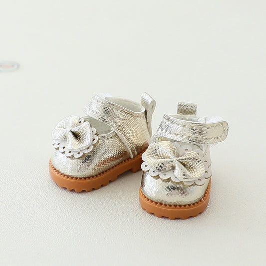 Pair of silver glittery baby shoes with brown soles on a light background